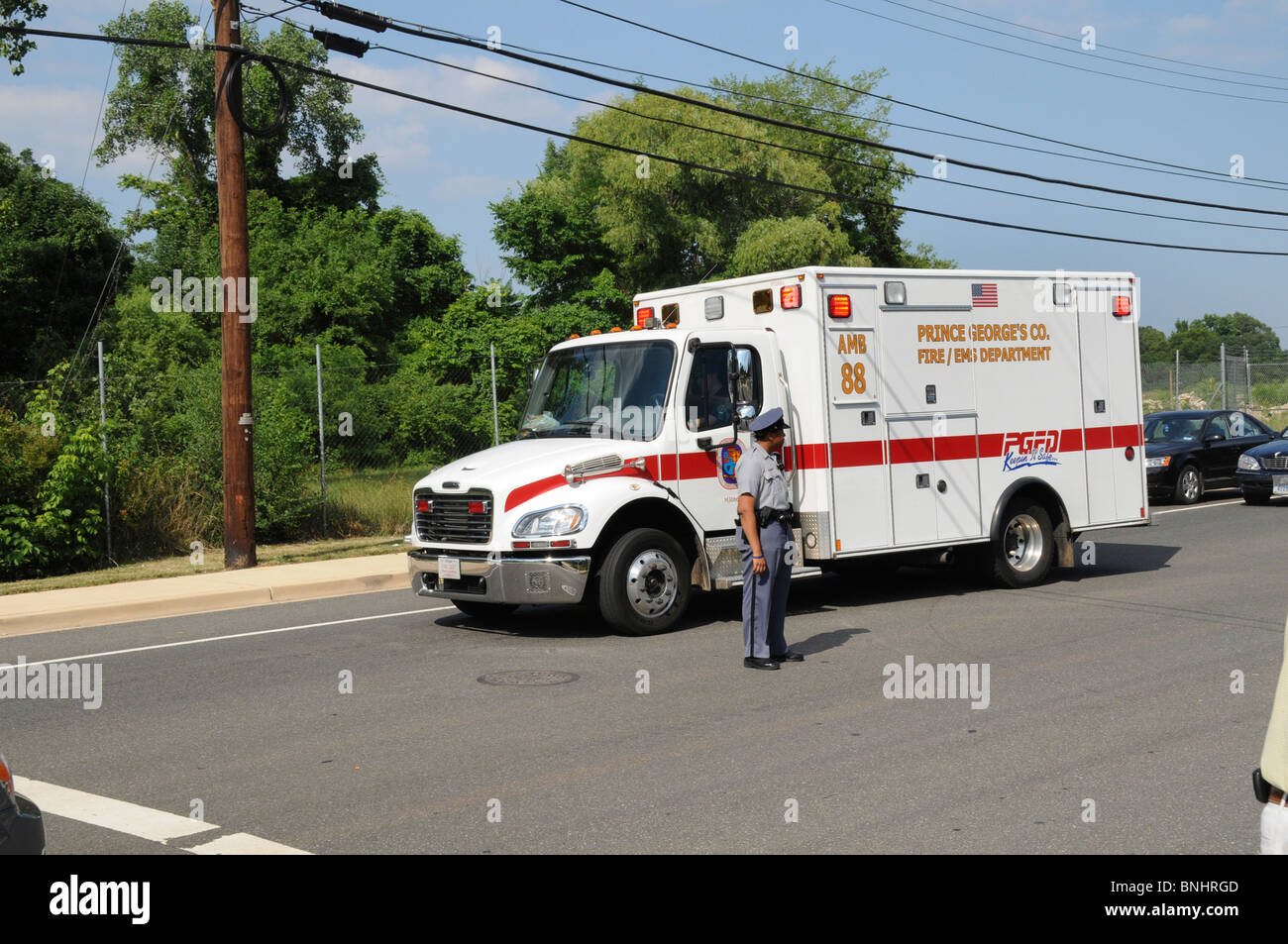 Ambulance responding on a call passes a police officer directing traffic in Fairmont  Heights, Maryland Stock Photo