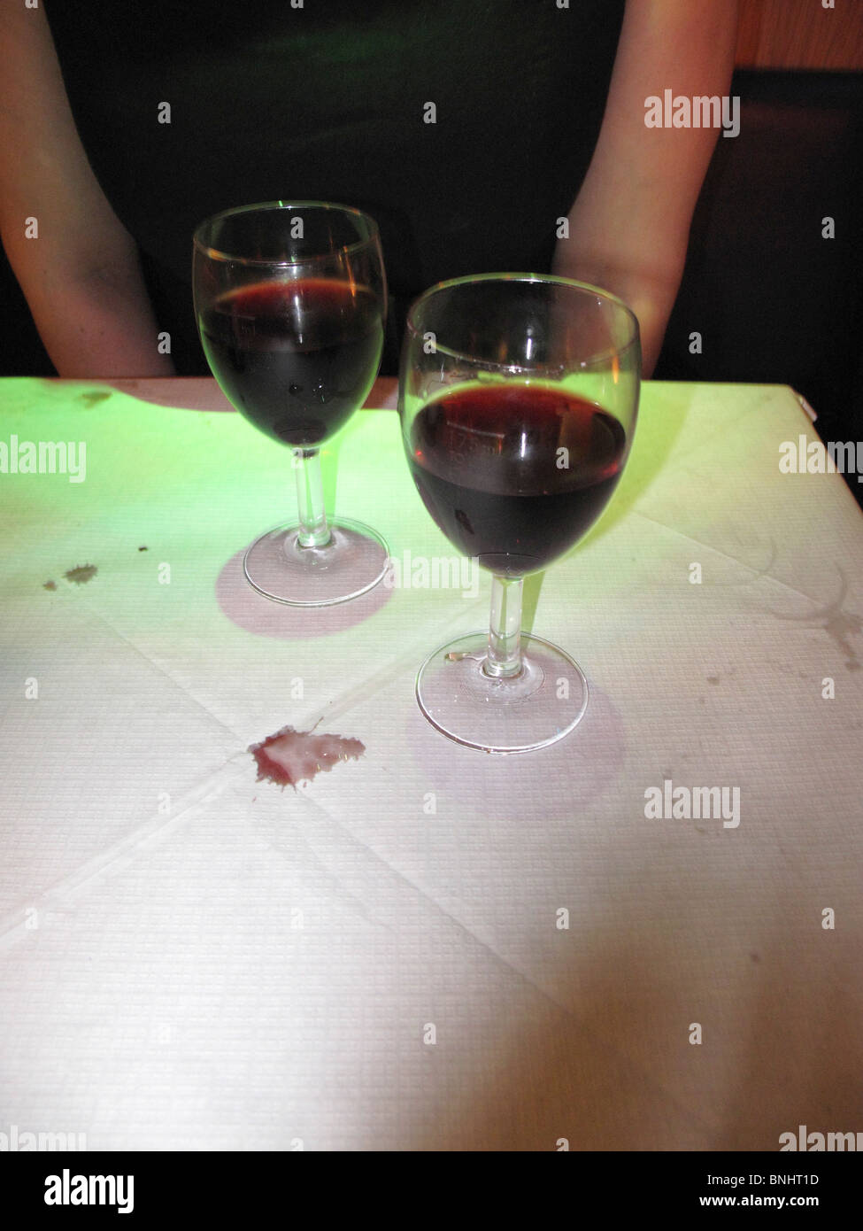Two glasses of red wine on restaurant table with wine stain on paper table cloth Stock Photo
