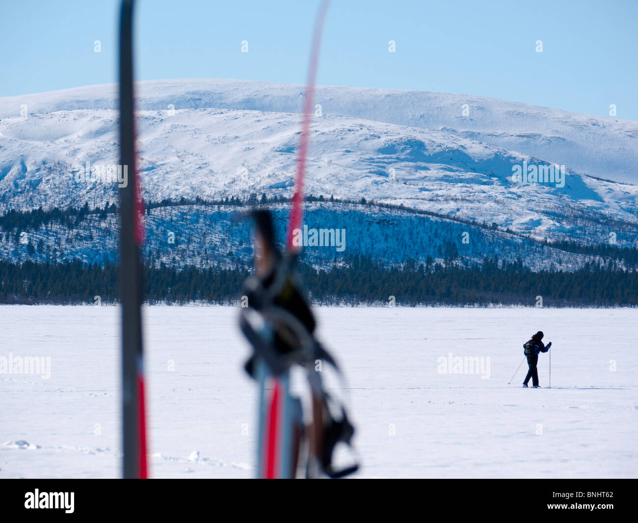 A skier makes his way above the frozen Kaalasjärvi lake in Kiruna, Lapland, Northern Sweden. Stock Photo