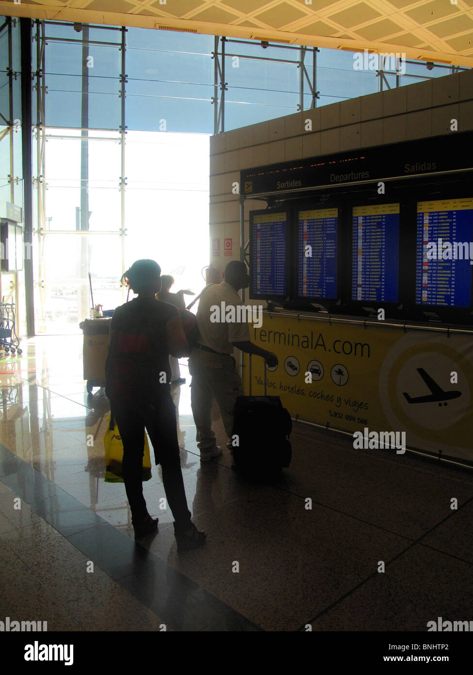 Passengers looking at departure screens at Barcelona Airport Stock Photo