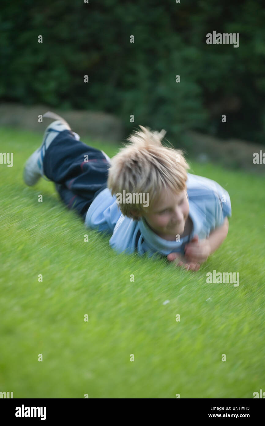 Young boy rolling down a hillside Stock Photo Alamy