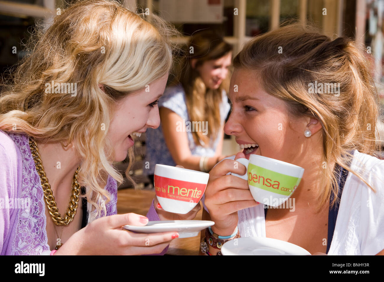 15 16 girl model release teenager break stop café coffee cups friends clap happily friends youth young people fun joke spare Stock Photo