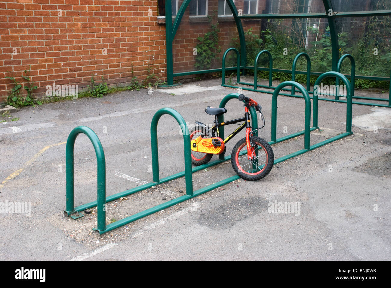 Lone children's bike in school bike stand Stock Photo