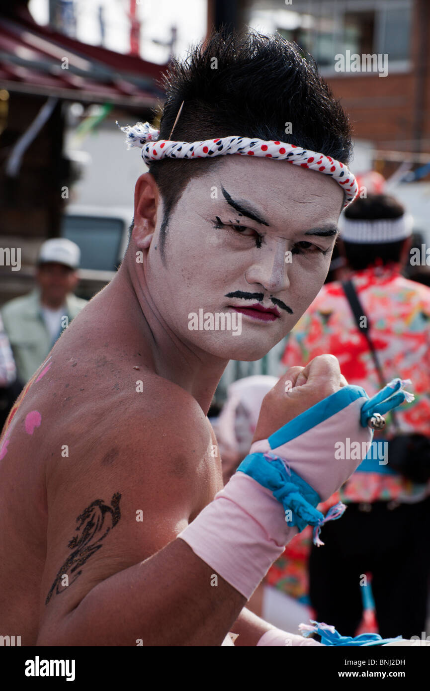 A Japanese man sports white face paint and a traditional headband during the Nagamochi dancing at the Onbashira Festival. Stock Photo