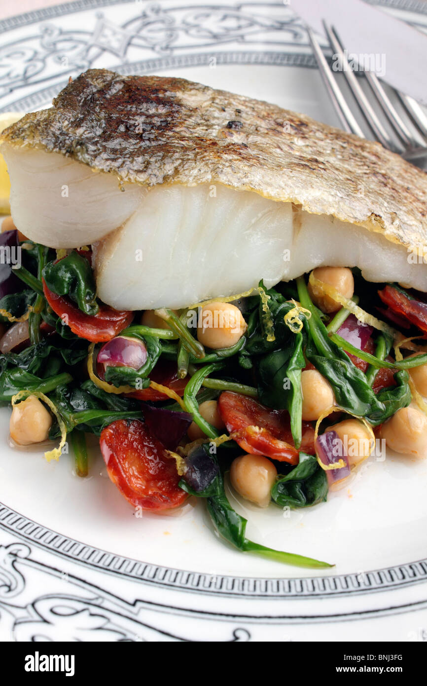 A baked fillet of pollock on a bed of garbanzo beans and spinach Stock Photo