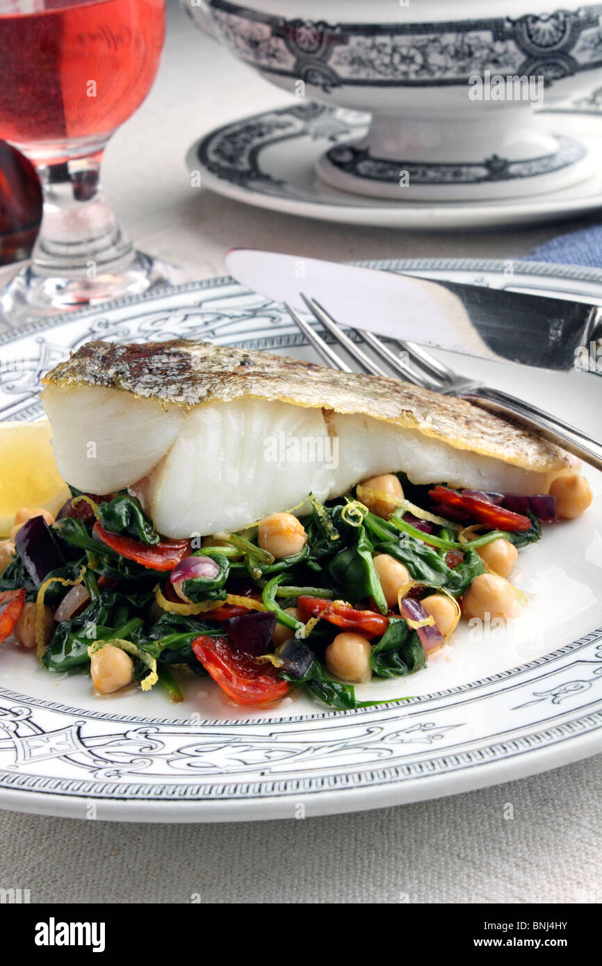 A baked fillet of pollock on a bed of garbanzo beans and spinach Stock Photo