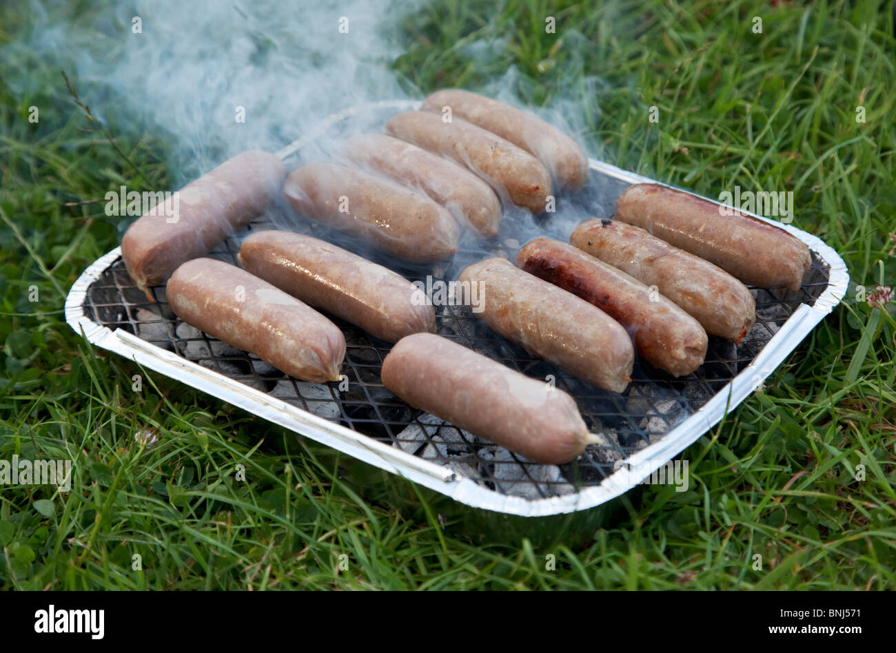 Sausages on single use barbecue Stock Photo - Alamy