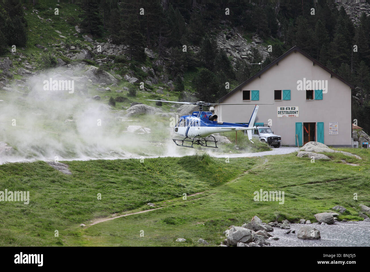 Helicopter Landing Next to a Restaurant at the Lac De Gaube in the French Pyrenees to Collect Supplies Stock Photo