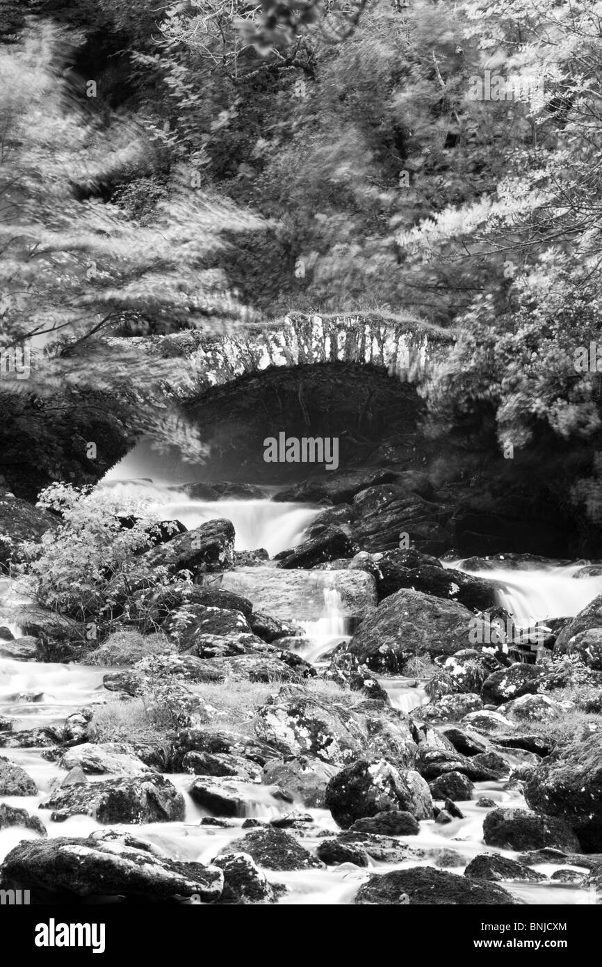 Stone bridge over fast flowing river Stock Photo - Alamy