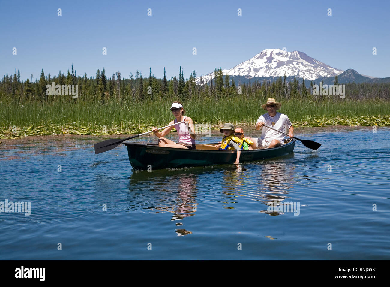 A family paddles a canoe on Hosmer Lake along the Cascade Lakes Highway