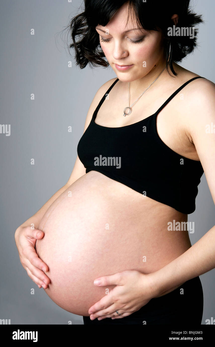 Beautiful pregnant mom holding her belly at nine months Stock Photo