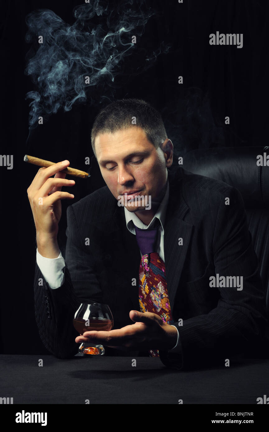 The man with a cigar and a glass of cognac. A dark background Stock ...