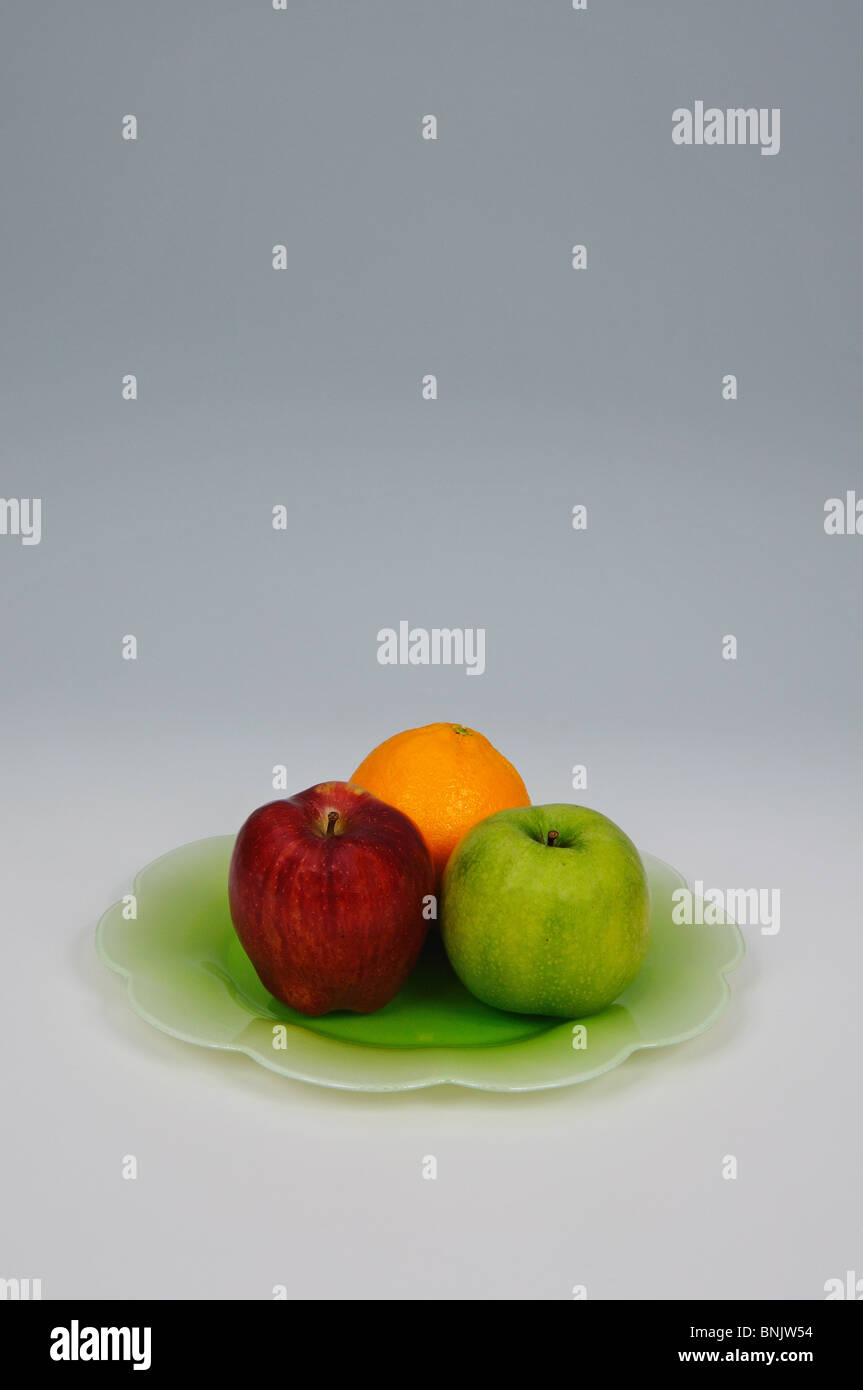 Two apples and an orange on a green plate, Andalucia, Spain, Western Europe. Stock Photo