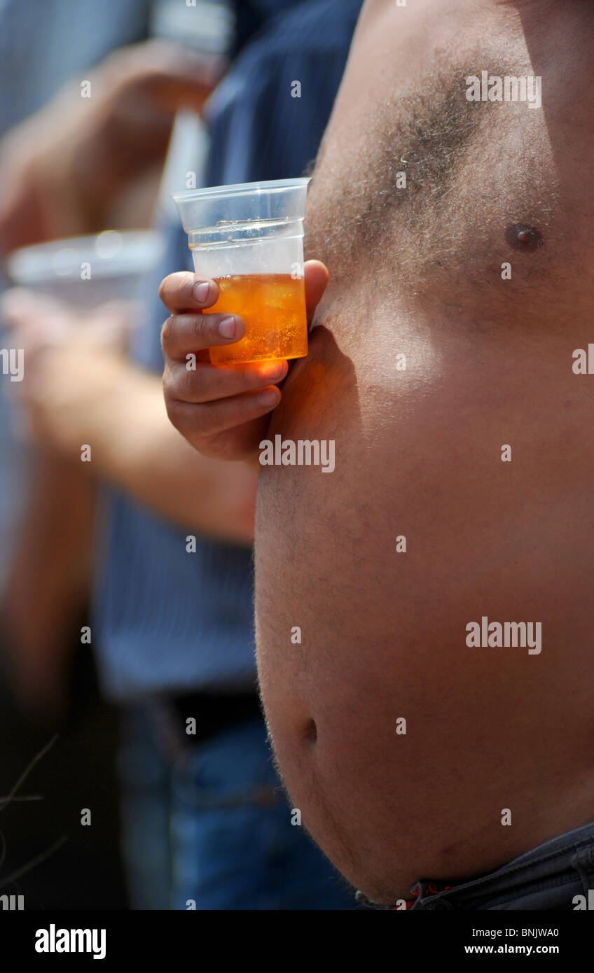 Bare chested man holding plastic glass of beer UK British Britain Stock Photo