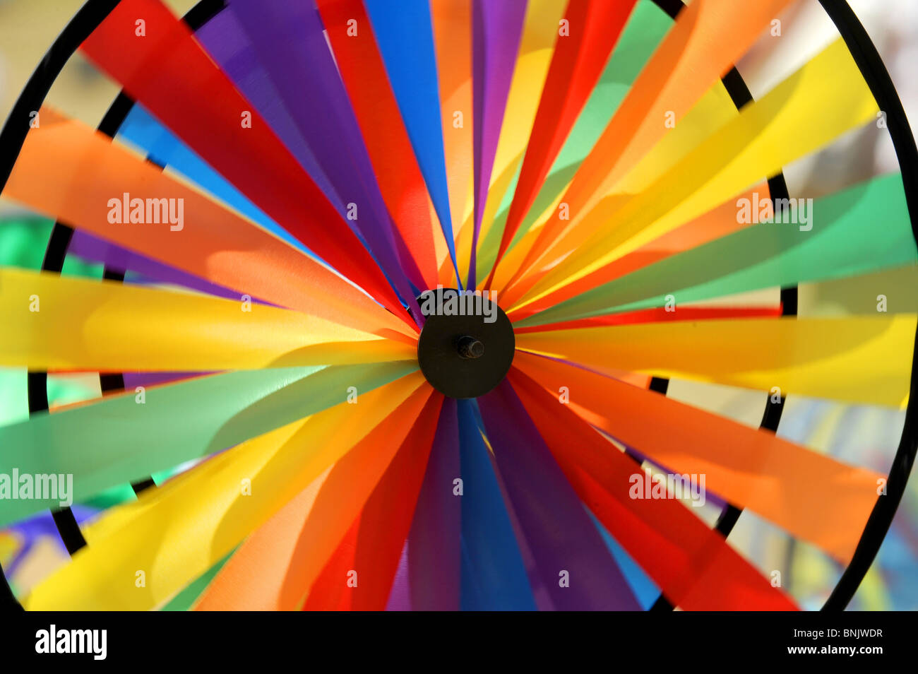 The colours of the rainbow on a toy windmill blowing in the breeze on summer day at Brighton Kite Festival UK Stock Photo