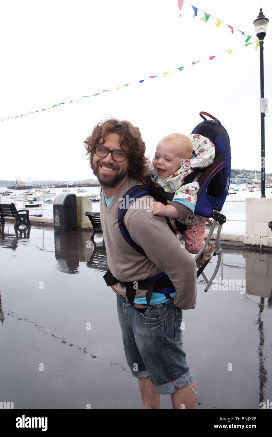 Man carrying a baby boy in a rucksack style baby carrier, Falmouth