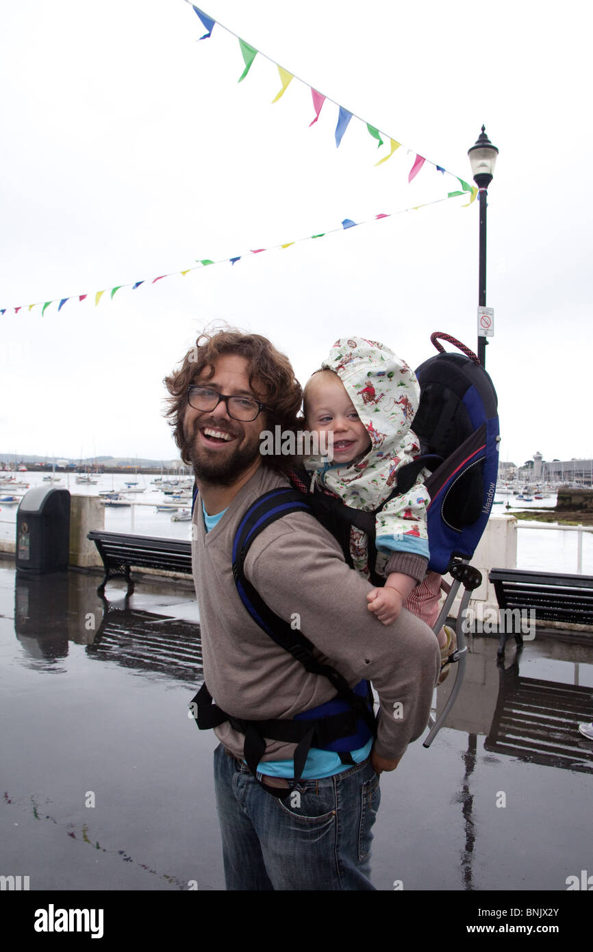 Man carrying a baby boy in a rucksack style baby carrier, Falmouth