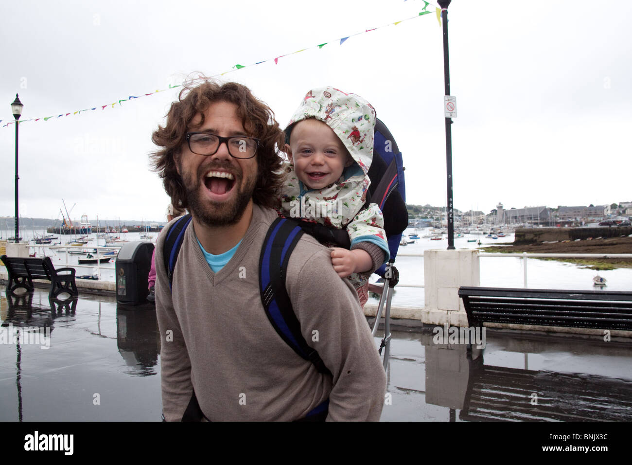 Man carrying a baby boy in a rucksack style baby carrier, Falmouth