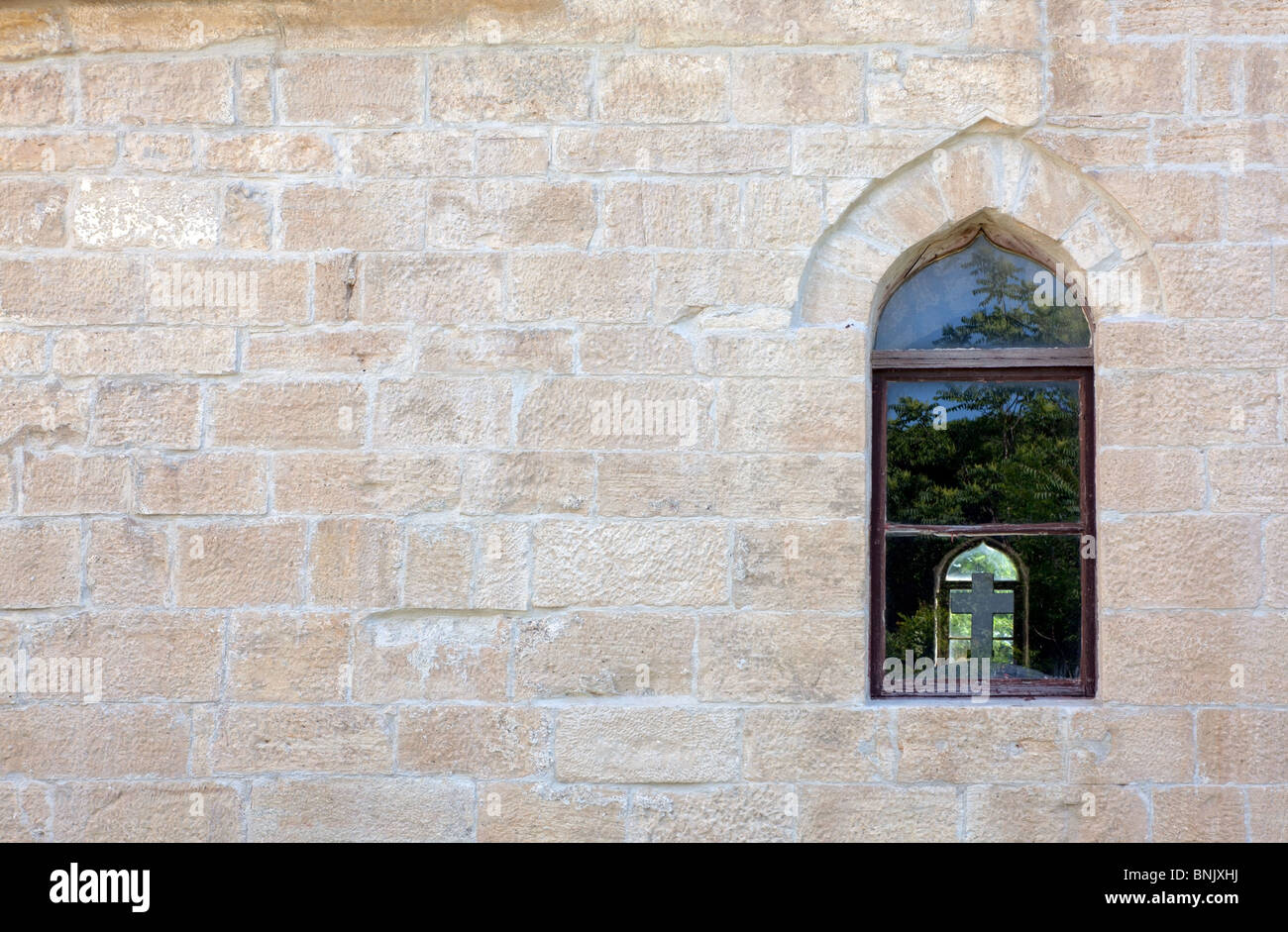 Old closed window on monastery wall, town Drnis - Croatia. Islamic window detail with a catholic cross inside. Stock Photo
