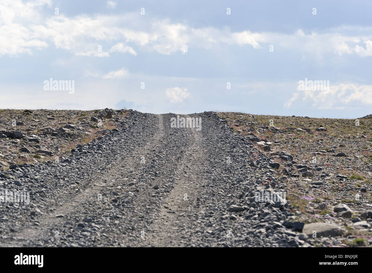 Gravel road in South Iceland, bright sky with clouds, uphill view Stock Photo