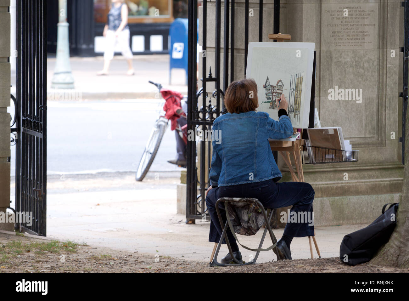 A female artist working outdoors painting a scene opposite her vantage point just off the High Street in Princeton, New Jersey, USA Stock Photo