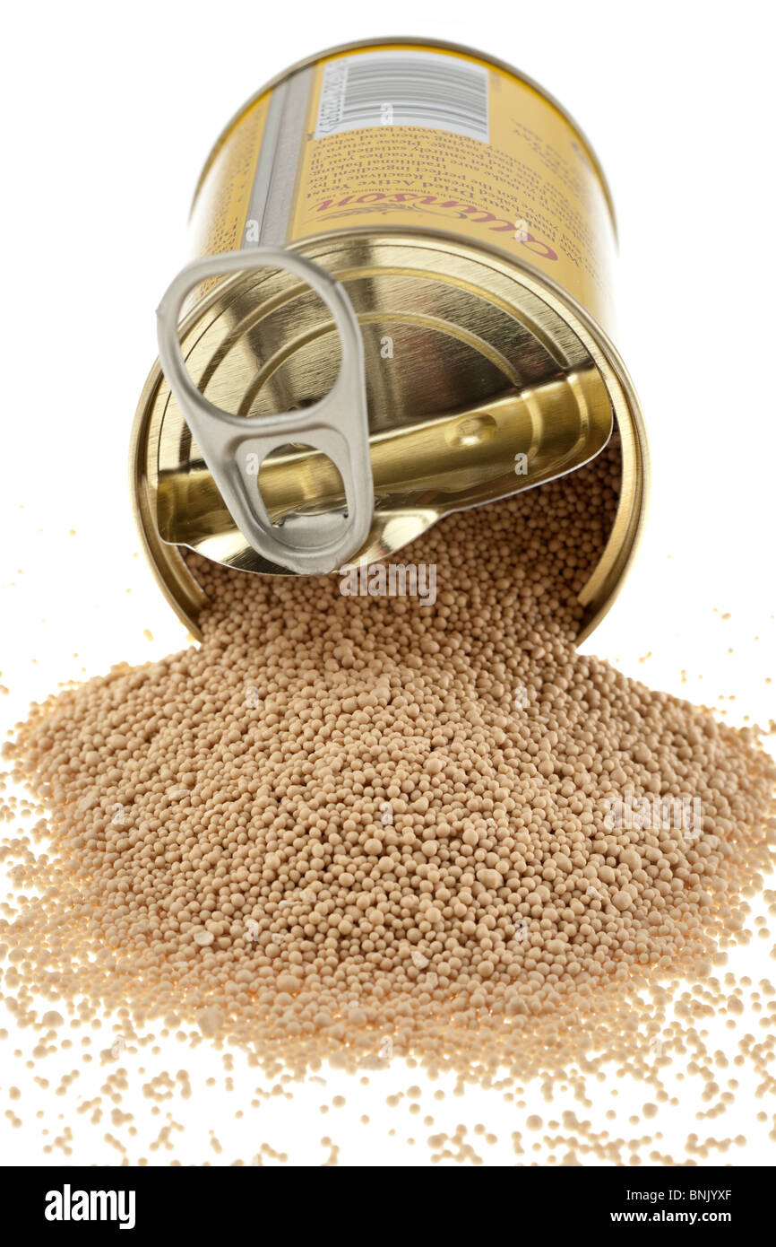 Tin of dried active yeast spilling onto a white surface Stock Photo