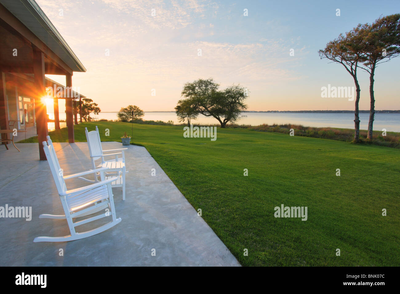 Rocking chairs on patio overlooking sunset over Bogue Sound, Country Club of Crystal Coast, Atlantic Beach, North Carolina, USA Stock Photo