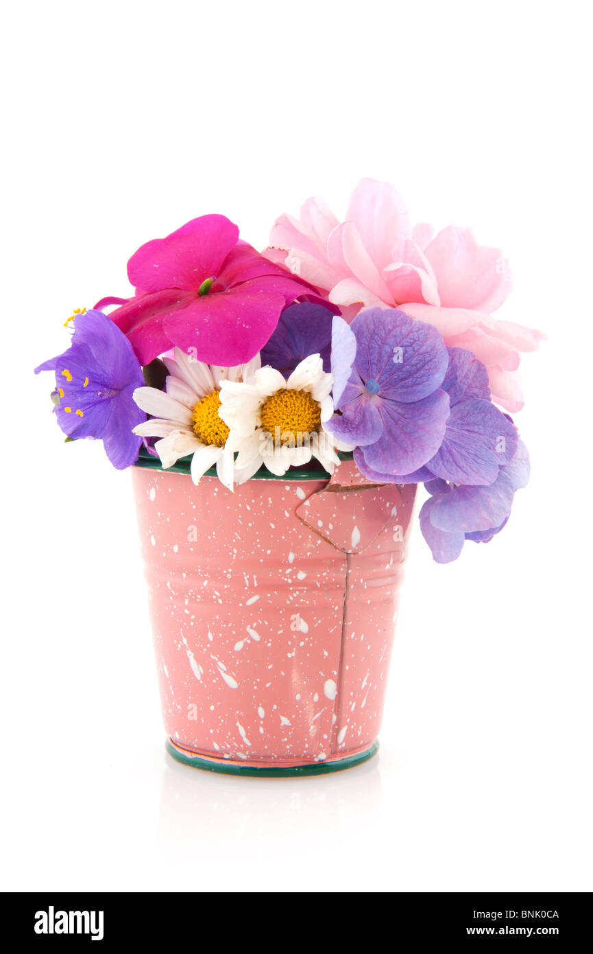 Pink little bucket with garden flowers isolated over white Stock Photo
