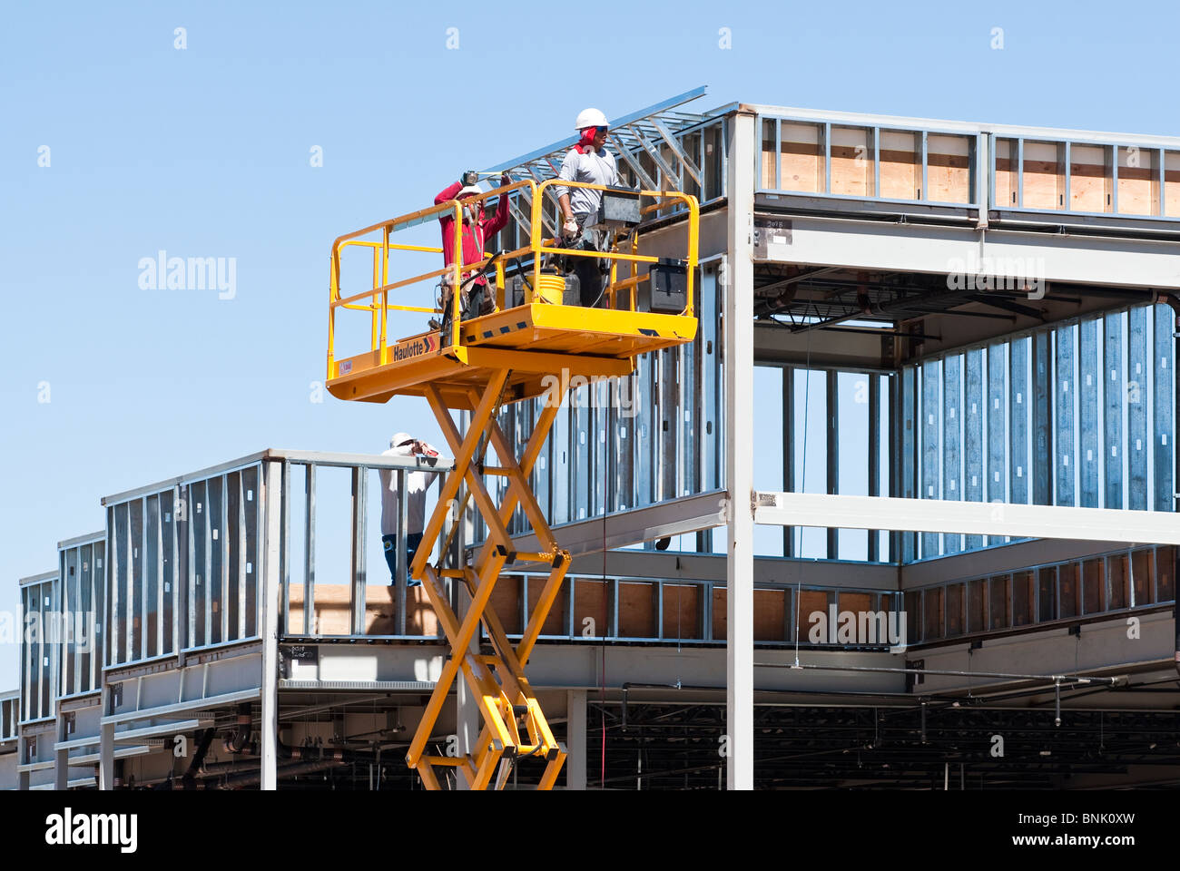 Construction workers on a scissor lift platform are assembling