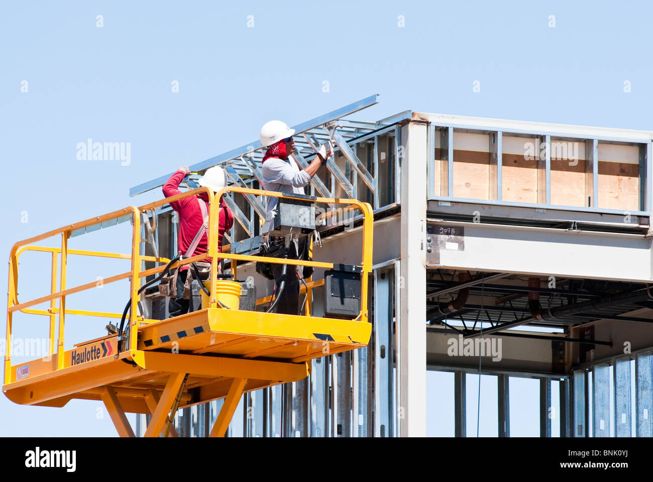 Construction workers on a scissor lift platform are assembling