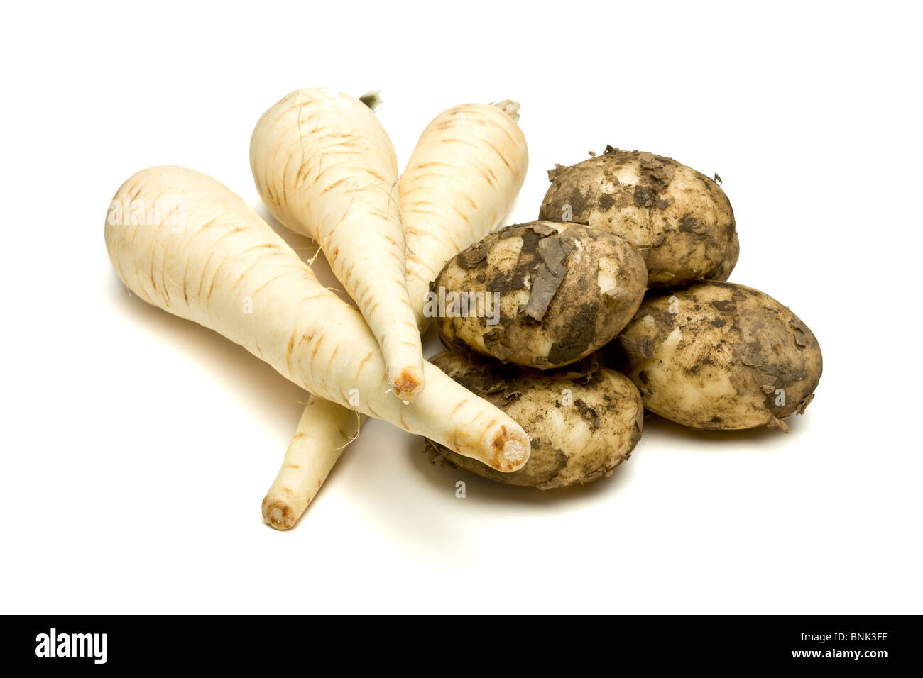 Root vegetables of Parsnip and New Potatoes from low perspective isolated against white background. Stock Photo