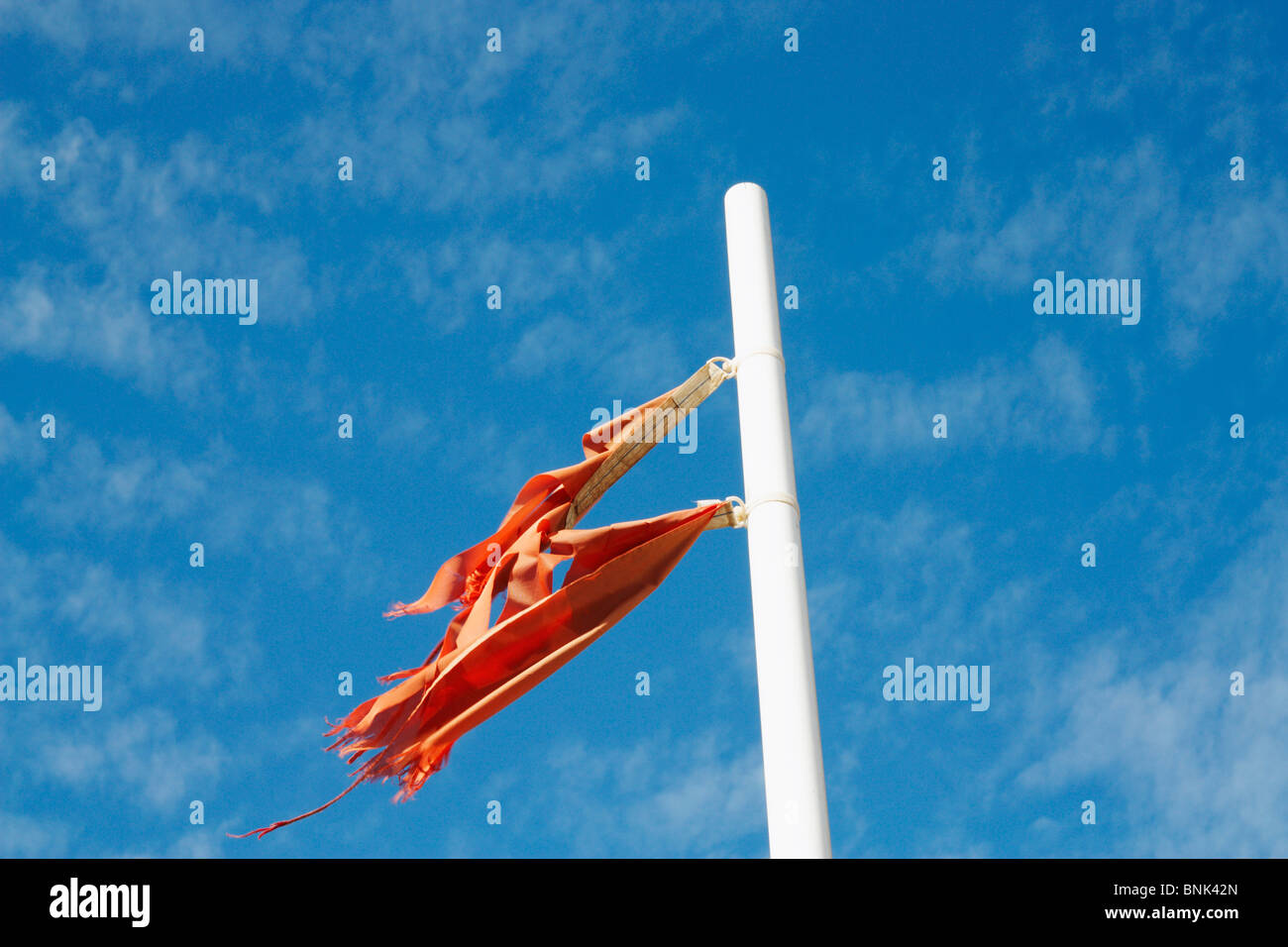 Tattered red flag on beach Stock Photo
