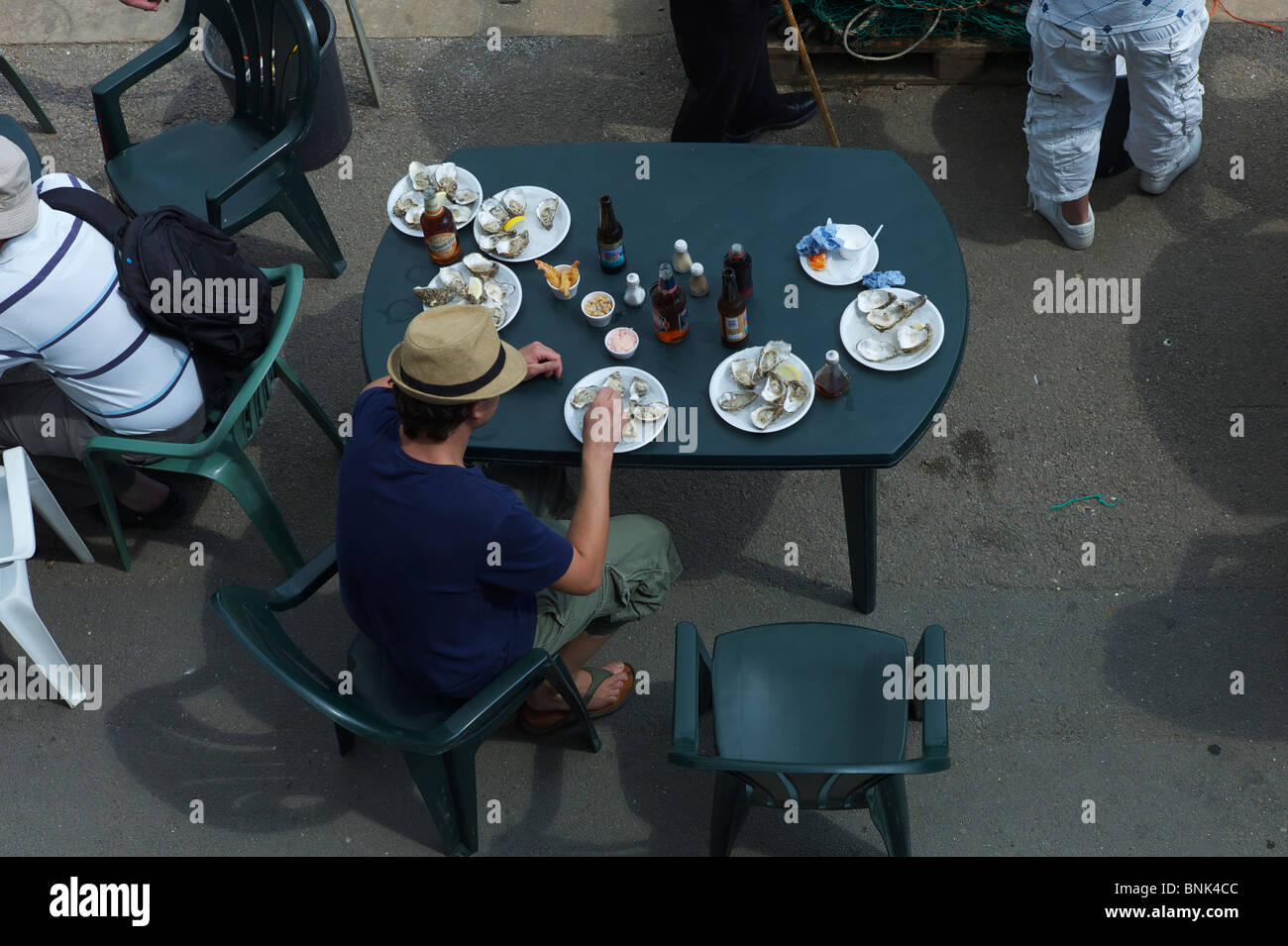 A man Sitting at table with plates of oysters and bottles of beer at