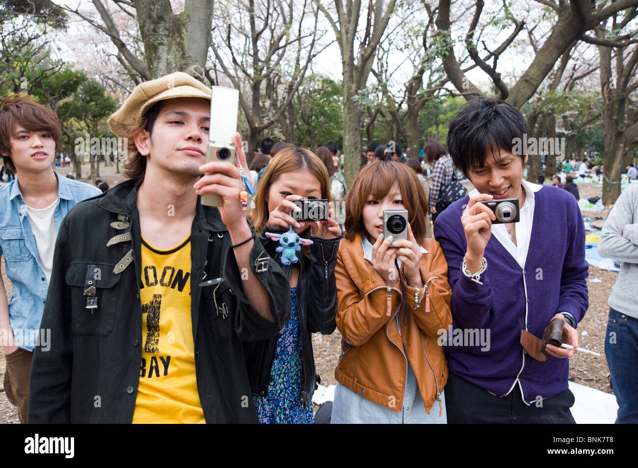 Trendy young teenagers taking photos with compact digital cameras in Yoyogi Park, Shibuya, Tokyo, Japan Stock Photo