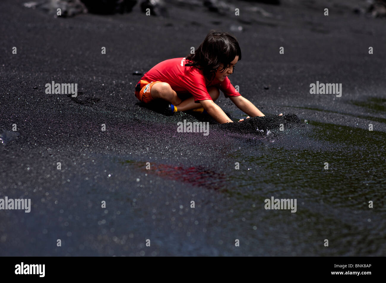 Child playing on a black sand beach in Hawaii Stock Photo - Alamy