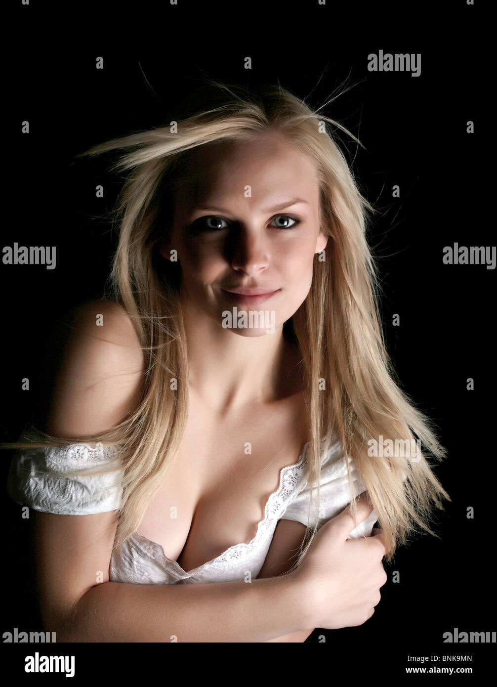 Beautiful blond on black background with her arms hugging her chest Stock  Photo - Alamy