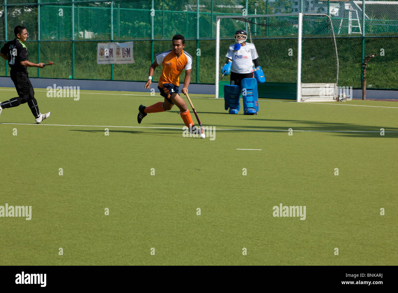 A hockey player runs for the ball in an inter university hockey match on Penang Island Stock Photo