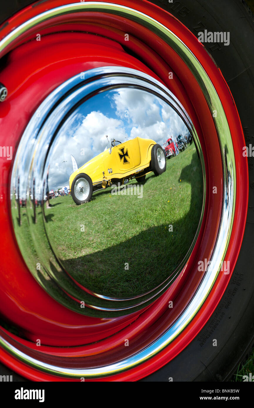 Reflection of a custom ford german iron cross hot rod car in a chrome wheel hub cap at a custom american car show. UK Stock Photo