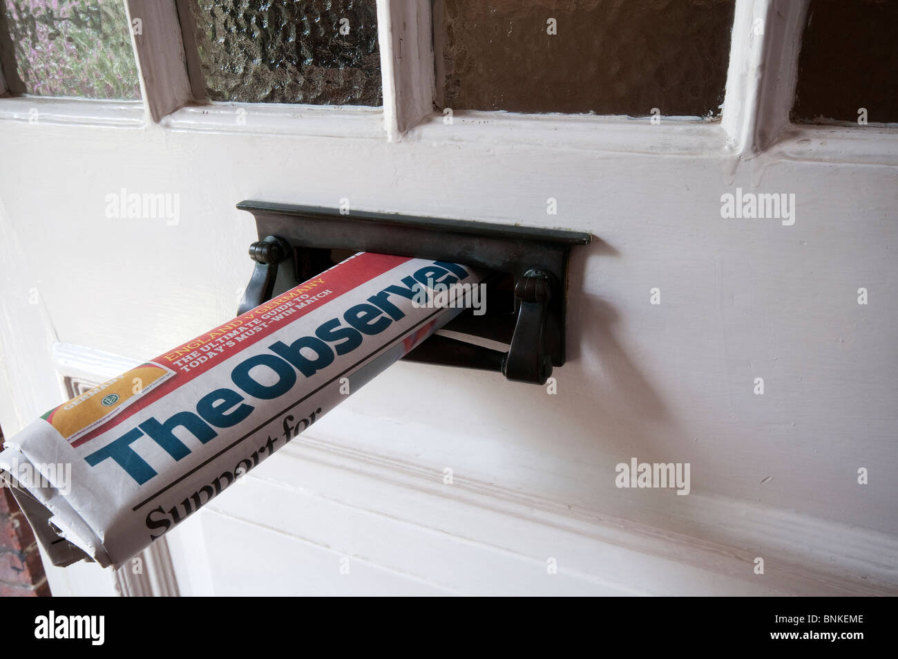 A copy of the English newspaper, The Observer, delivered to a house and sticking out of the letterbox Stock Photo