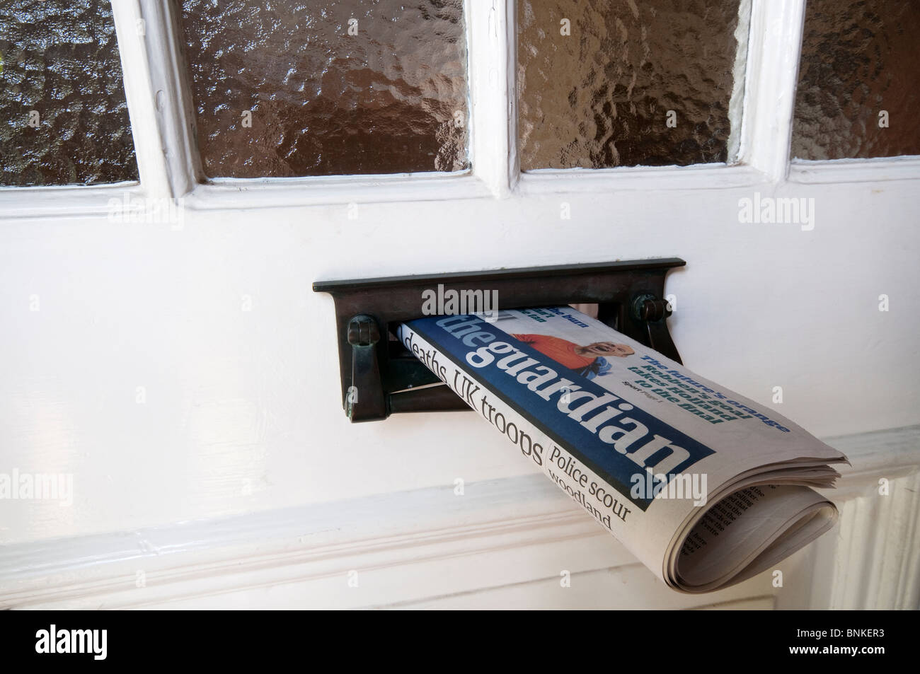 A copy of the English newspaper, The Guardian, delivered to a house and sticking out of the letterbox Stock Photo