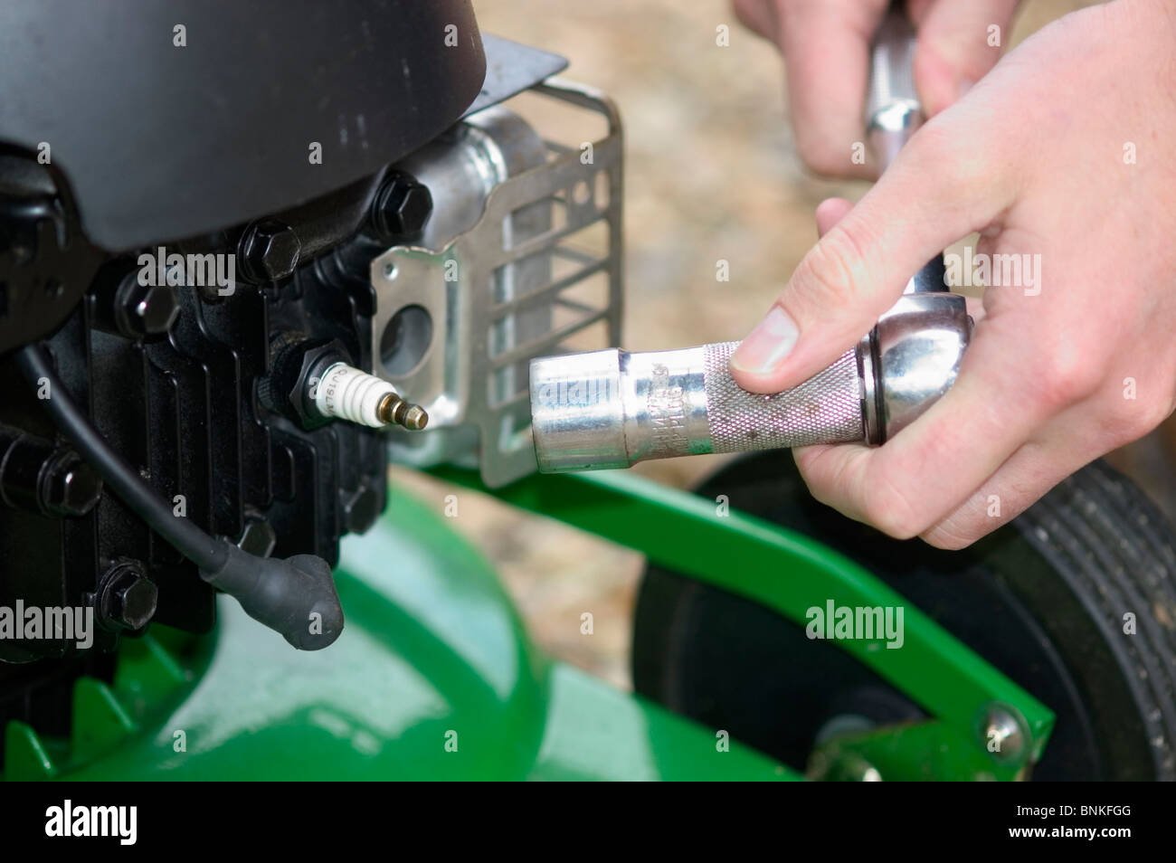 Removing & checking spark plug on a petrol driven rotary mower Stock Photo