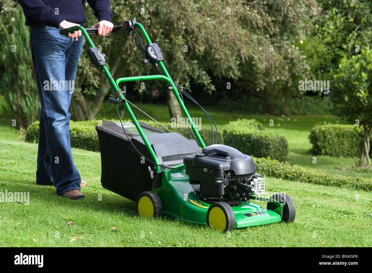 Mowing a garden lawn with a John Deere rotary mower Stock Photo
