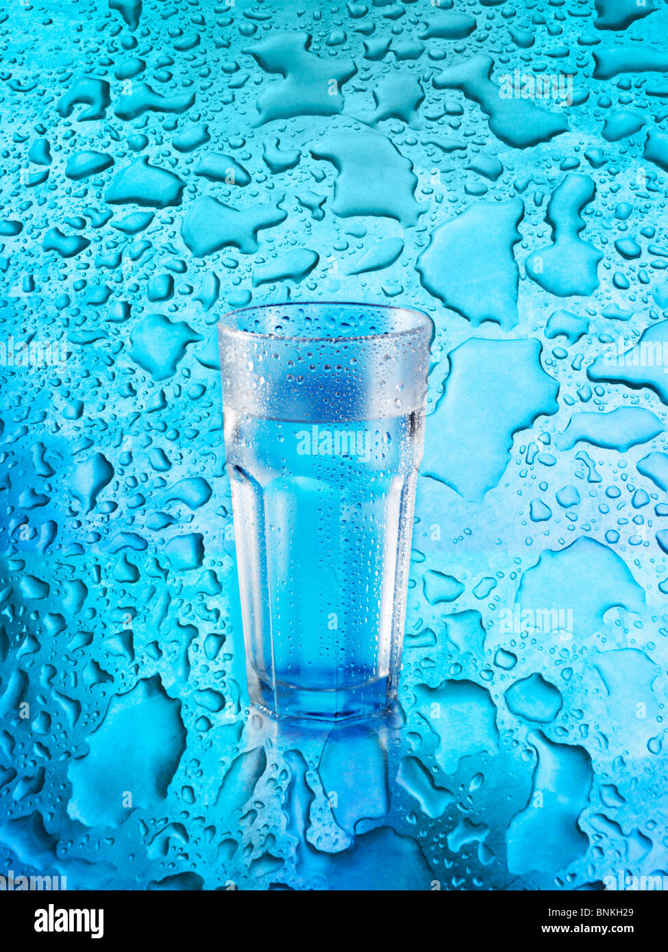 A glass of water on blue background covered in water droplets Stock ...
