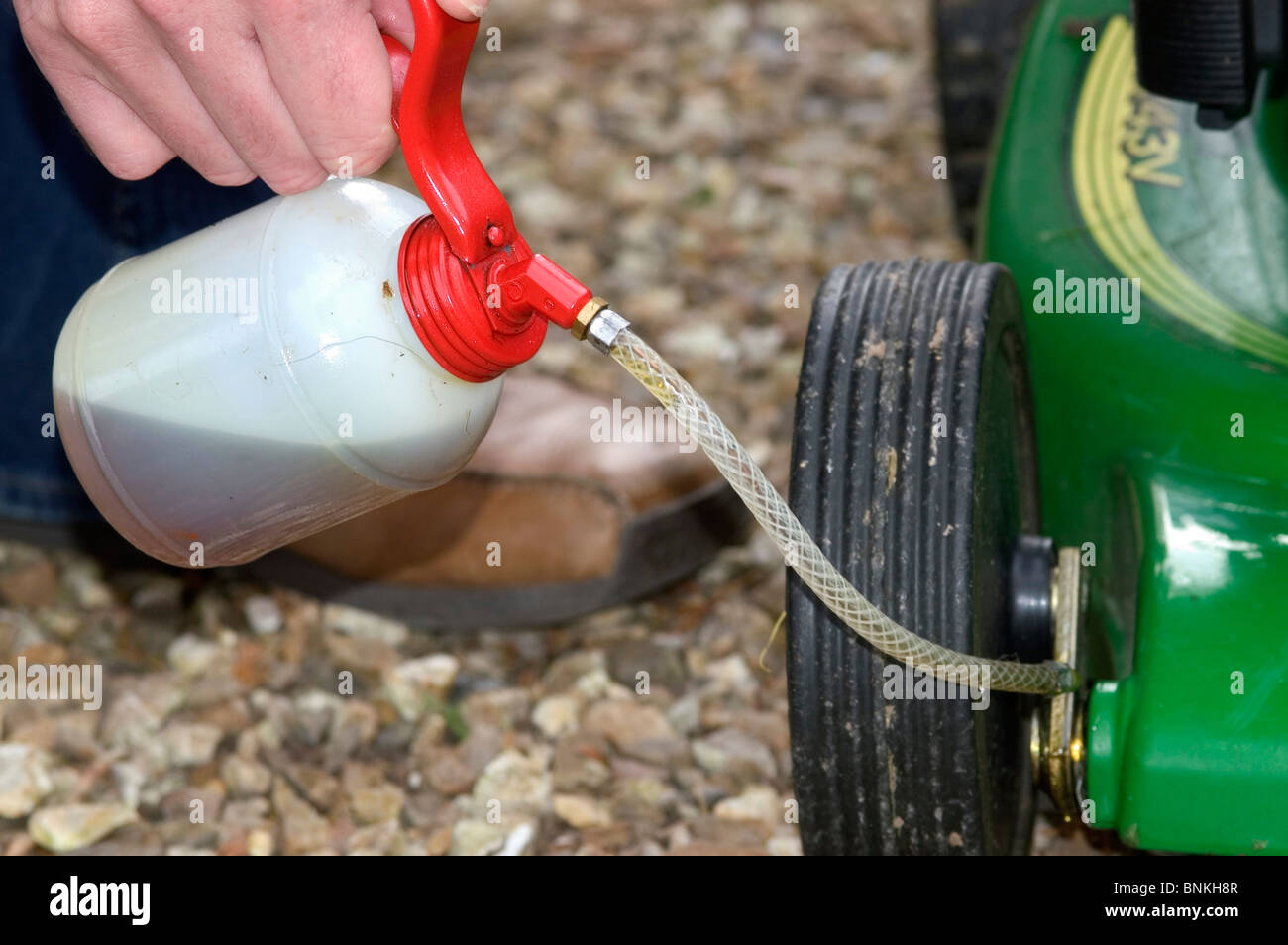 Oiling the moving parts on a petrol driven rotary mower Stock Photo