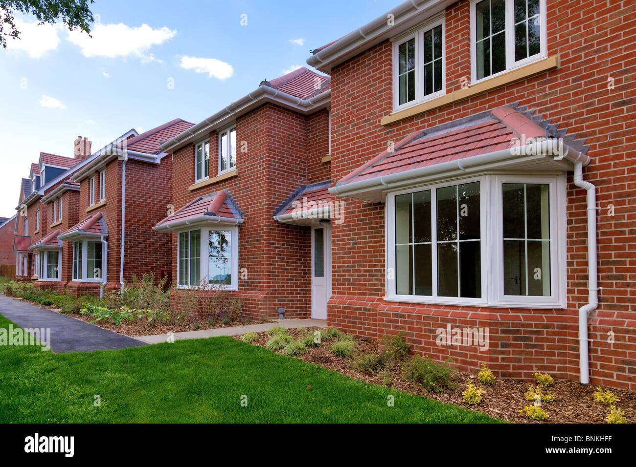 Photo of a row of brand new empty houses for sale on a housing development. Stock Photo