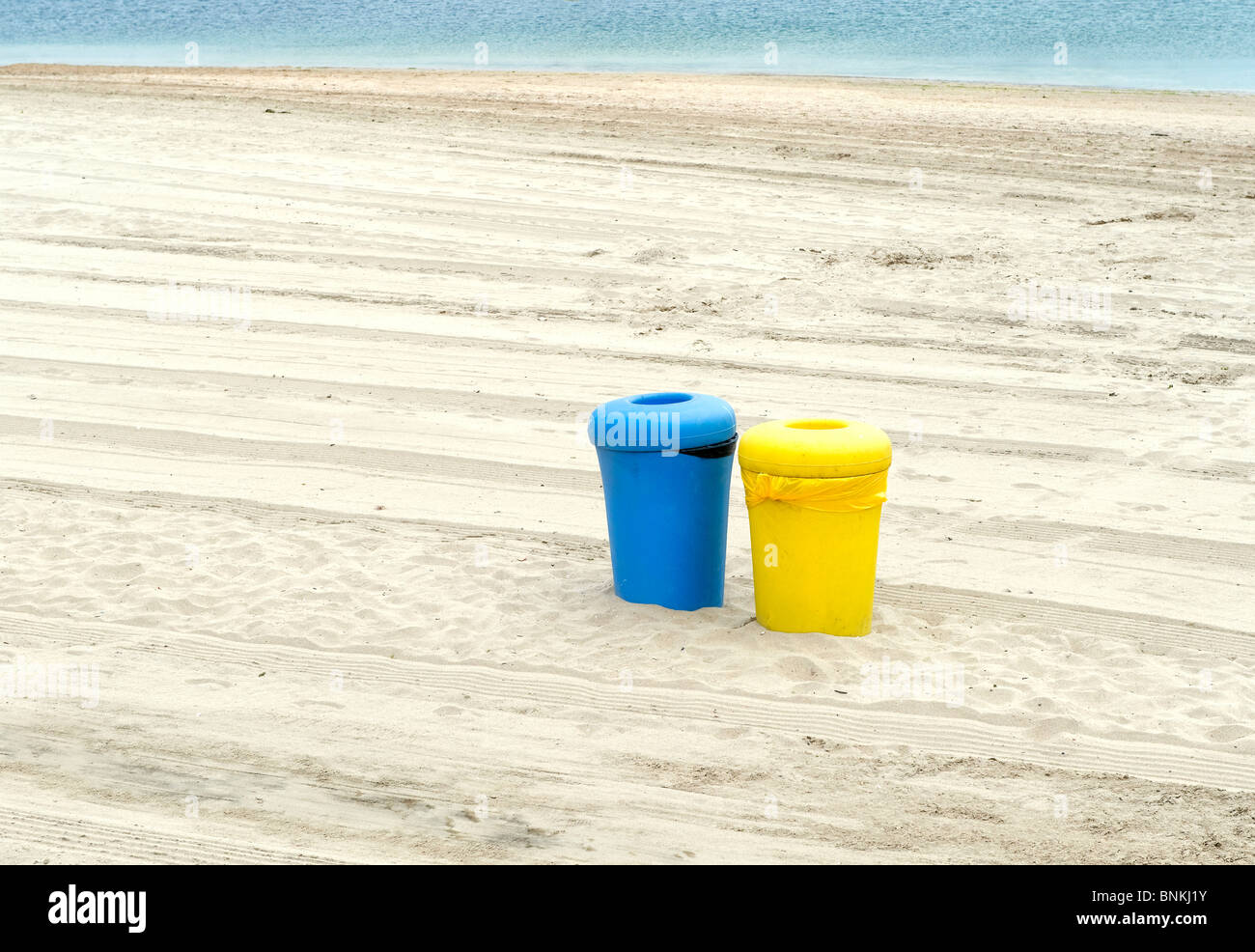 Two Colorful Waste Bins on a Deserted Beach Stock Photo