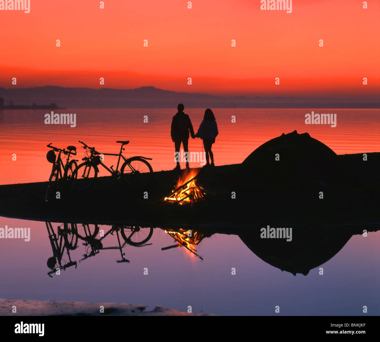 Switzerland scenery lake sea sundown campfire pair couple bicycles bikes bicycles tent camping romantically bicycle driving Stock Photo