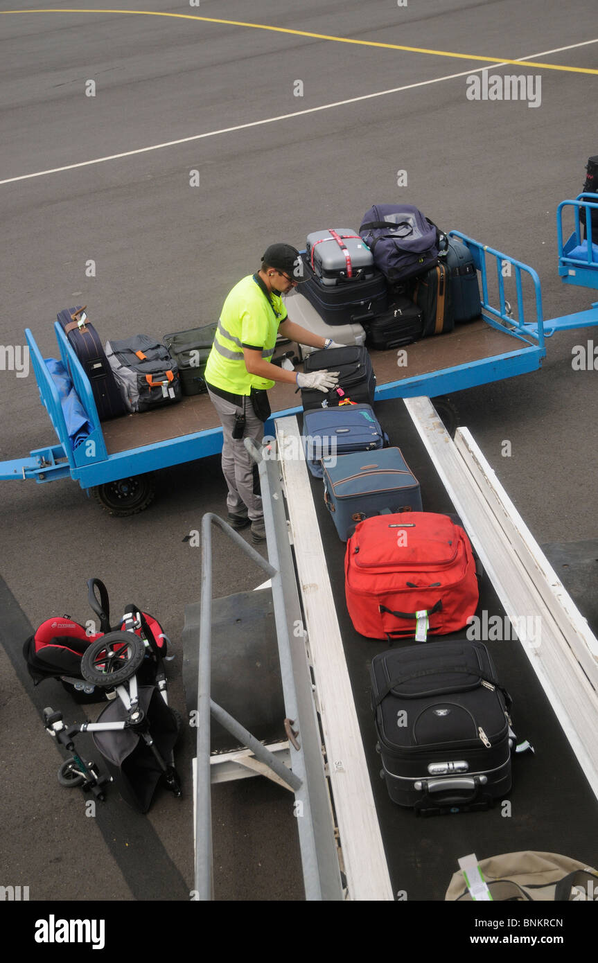 Airport baggage handler loading bags from a trolley onto an aircraft at Beziers International Airport southern France EU Stock Photo
