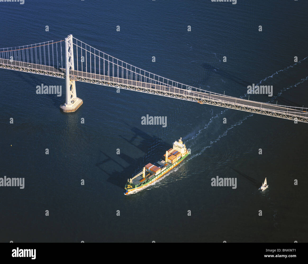 aerial view above Linea Mexicana container ship  passing under San Francisco Oakland Bay Bridge California Stock Photo