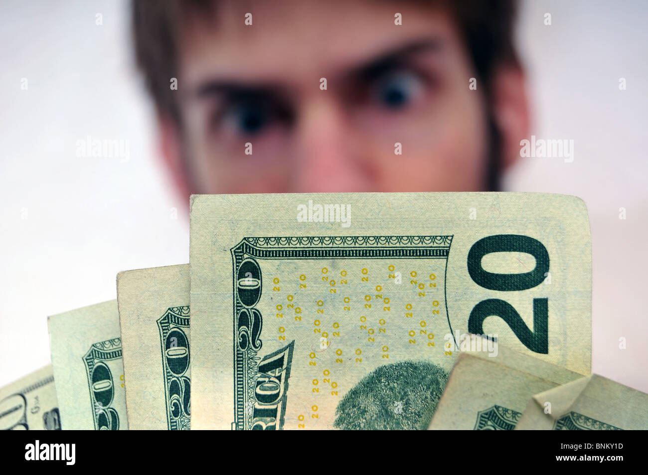 Blurred Man in background staring at a wad of cash, with an intentional slightly dramatic blue tint. Stock Photo